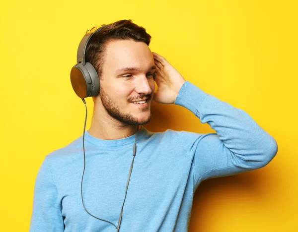 Jonge knappe man draagt blauwe trui luisteren naar muziek in hoofdtelefoon — Stockfoto