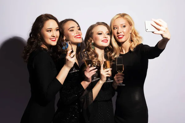 Feest-, feest- en mensenconcept - vier modieuze jonge vrouwen die champagne drinken en een selfie nemen — Stockfoto