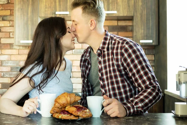 一对恋爱中的年轻夫妇在厨房里吃早餐 喝咖啡和羊角面包 还有爱情和柔情 生活方式和人的概念 — 图库照片
