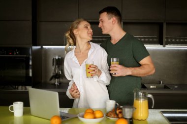 Yaşam tarzı, aşk ve insan konsepti - güzel genç bir çift ayakta ve evde bir mutfakta sarılıyorlar