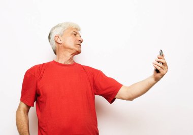 Selfie zamanı. Belden yukarı portre mutlu emekliler elini uzatmış ve gülüyor. Beyaz arkaplanda izole