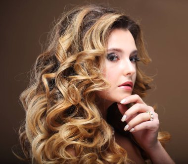 Esmer, sarışın, uzun, sağlıklı ve parlak kıvırcık saçlı bir kadın. Dalgalı saç stili olan güzel bir kadın..