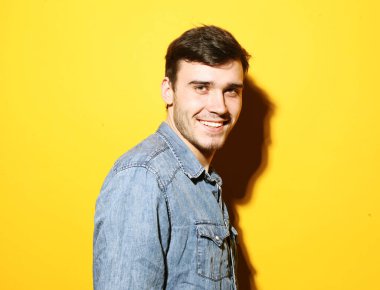 Sarı arka planda duran yakışıklı, modaya uygun genç bir erkek model.