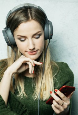 İnsanlar ve teknoloji kavramı - kulaklıklı mutlu genç kadın akıllı telefondan müzik dinliyor.