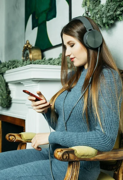 Νέα Χρόνια διάθεση. Νεαρή ξανθιά γυναίκα φοράει casual ακούει χριστουγεννιάτικη μουσική. — Φωτογραφία Αρχείου