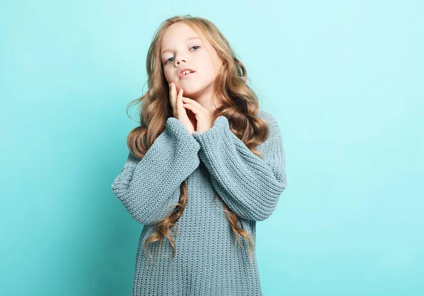 Adorabile bambina con lunghi capelli biondi ricci in posa su uno sfondo blu — Foto Stock