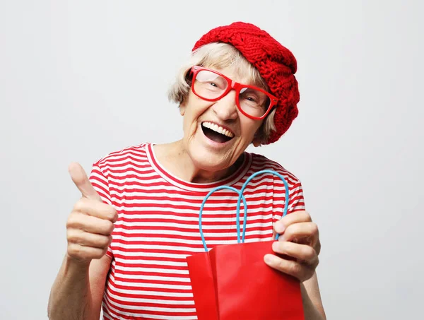 Lifestyle and people concept: elderly woman pulls out a gift from the bag — Stock Photo, Image