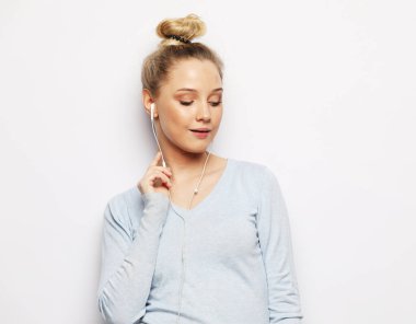 Kulaklıklı hoş bir bayan beyaz arka planda kameraya bakıp gülüyor..