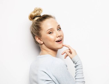 Cilt bakımı ve makyaj konsepti. Sarışın genç bir kadının doğal makyajla parlayan cildini gösteren, kameraya gülümseyen..