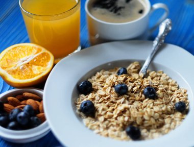 Sağlıklı kahvaltı, yemek ve diyet konsepti - beyaz tabakta taze böğürtlen, portakal suyu ve süt, mavi ahşap arka plan.
