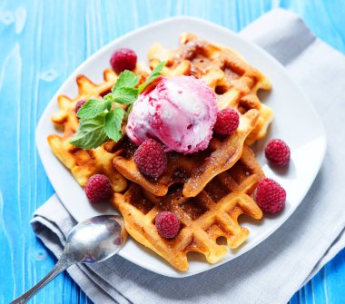 Taze böğürtlenli Belçika waffle 'ları ve mavi ahşap arka planda dondurma.