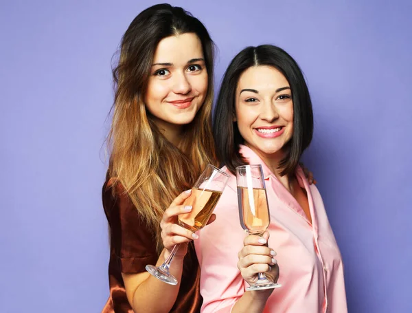 Två unga vackra kvinnor klädda i pyjamas dricker champagne och har kul — Stockfoto