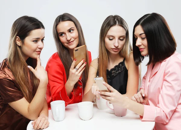 携帯電話とパジャマで4人の美しい女性の友人 — ストック写真