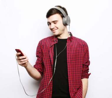 Kulaklık takan ve cep telefonu tutan genç bir adam..