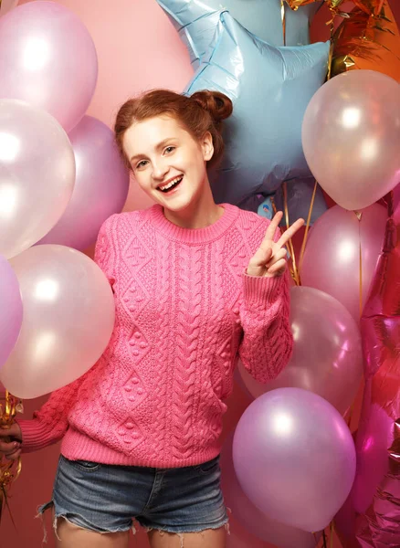 Beautiful young redhair woman wearing pink sweater with colored balloons. — Stock Photo, Image
