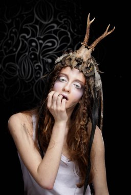 Parlak makyajlı, örgülü ve kafasında kafatası olan genç bir kadın.