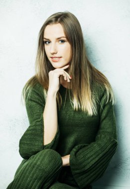 Genç, kahverengi saçlı, uzun saçlı yeşil örgü elbiseli, gevşemiş ve dinlenmiş bir kadın..