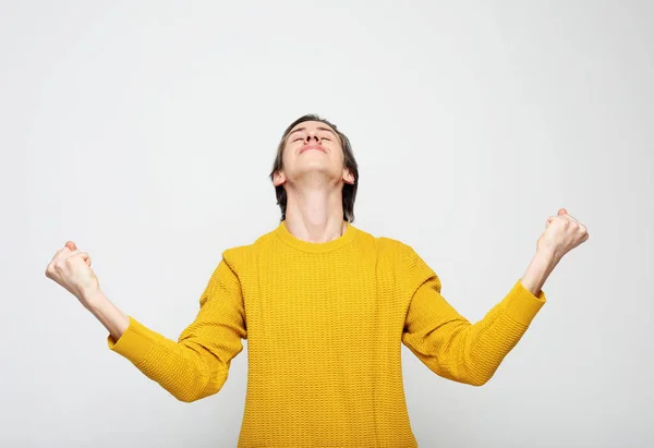Young man wearing yellow sweater very happy and excited doing winner gesture with arms raised — Stock Photo, Image