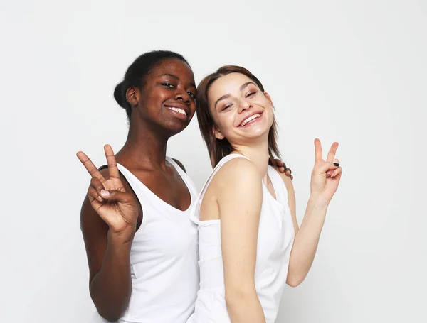 Dos jóvenes mujeres multirraciales muestran signo de victoria y sonriendo a la cámara — Foto de Stock