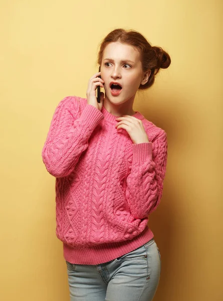 Funny young redhead woman sing song in microphone and posing isolated on yellow background in studio. — Stock Photo, Image