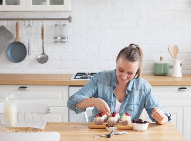 Genç kadın çörekleri böğürtlenlerle süslüyor.
