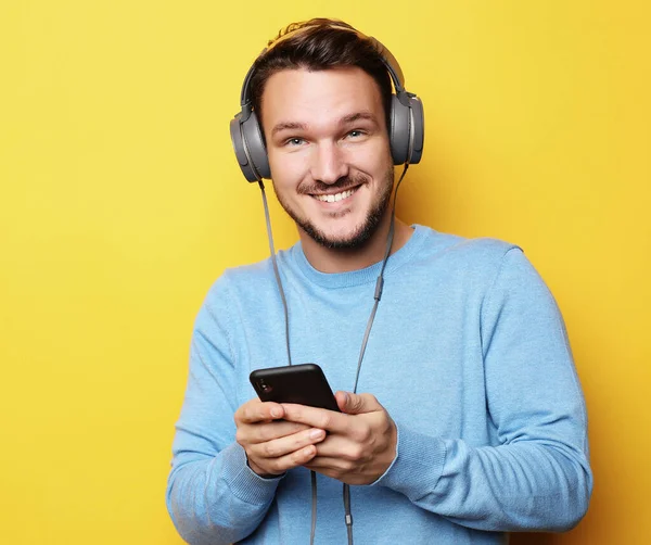 Jongeman met een koptelefoon en een mobiele telefoon — Stockfoto