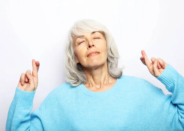 Senior blanke vrouw denken over iets aangenaams en het maken van wens met gekruiste vingers geïsoleerd — Stockfoto