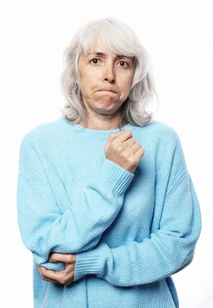 Oudere vrouw in een blauwe trui pijn in de elleboog gezondheidsproblemen over witte achtergrond — Stockfoto