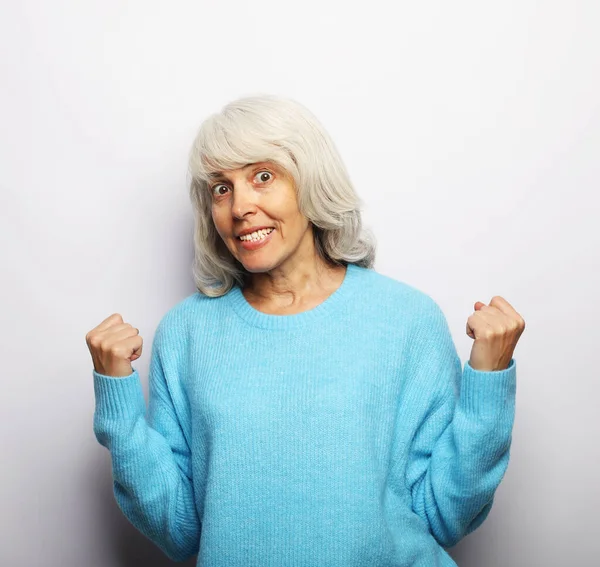 Portret van een volwassen vrouw met blauwe trui die een winnaarsgebaar maakt — Stockfoto