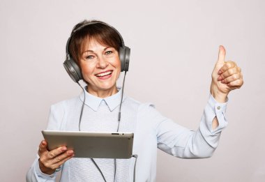 Yaşam tarzı, tehnoji ve insan konsepti: Yaşlı bir kadın tablet kullanarak yeni bir meslek ediniyor. Öğrenmeyi dinler.