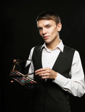 Stüdyoda poz veren profesyonel makyözün elinde gölgeler paleti var..