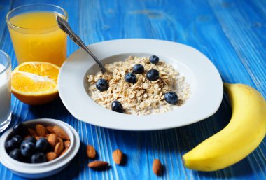 Beyaz tabakta taze böğürtlen, portakal suyu ve sütle yulaf ezmesi