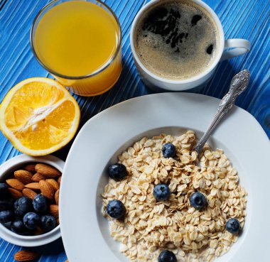 Beyaz tabakta taze böğürtlen, portakal suyu ve sütle yulaf ezmesi