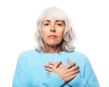 Yaşlı bir kadın ellerini kalbine yakın tutuyor, kalbi acıyor, yaşlı kadın heyecan verici duygular yaşıyor.