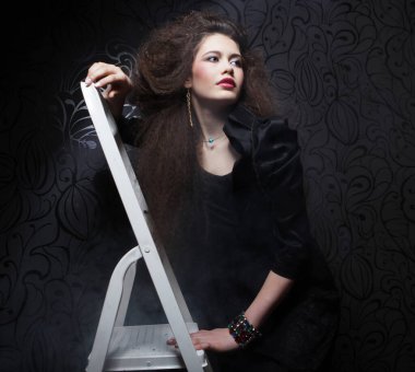 Merdivenin yanında kıvırcık saçlı güzel bir kadın..