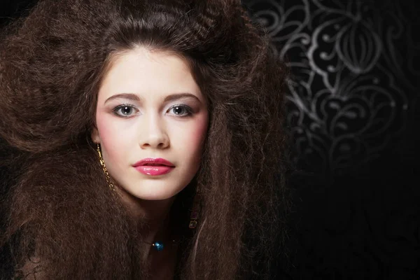 Όμορφη νεαρή γυναίκα με μακριά σγουρά μαλλιά και βραδινό μακιγιάζ φορώντας μαύρο φόρεμα και jewerly — Φωτογραφία Αρχείου