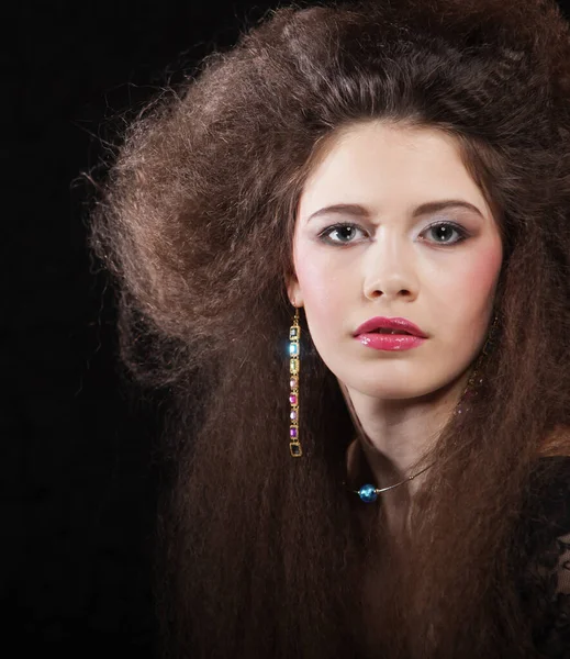Όμορφη νεαρή γυναίκα με μακριά σγουρά μαλλιά και βραδινό μακιγιάζ φορώντας μαύρο φόρεμα και jewerly — Φωτογραφία Αρχείου