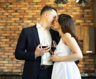 Genç evli çift şarap içip mutluluklarına, romantizmlerine ve şefkatlerine gülümsüyor.