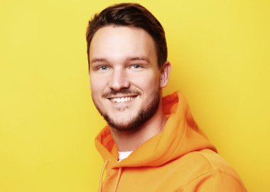 Sarı arka planda duran zeki bir gencin portresi.