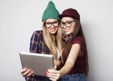 İki hippi bayan arkadaş dijital tablet kullanıyor. Stüdyo gri vackground üzerinde çekim yapıyor.