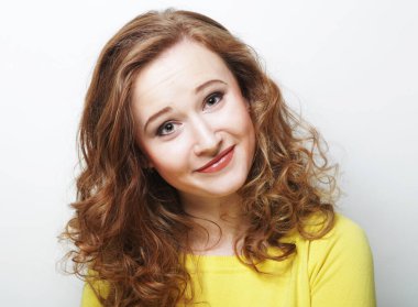 Yaşam tarzı, duygu ve vücut dili kavramı: Kıvırcık saçlı ve tatlı gülüşlü güzel genç kadın beyaz arka planda yalnız poz veriyor.