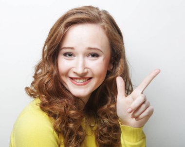 Yaşam tarzı, duygu ve vücut dili kavramı: Gülümseyen genç kadın boş fotokopi alanını işaret ediyor