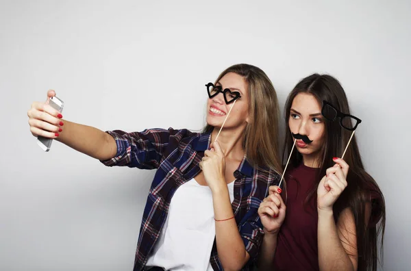 Dos amigas adolescentes en traje hipster hacen selfie en un teléfono. —  Fotos de Stock
