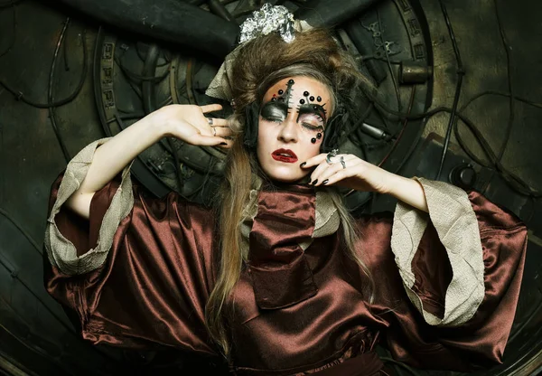 Mulher com maquiagem brilhante em um cenário steampunk mantém com as mãos para correntes vermelhas. — Fotografia de Stock