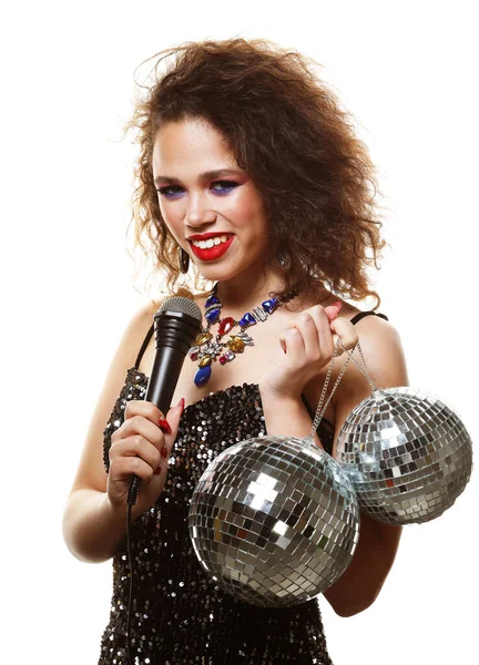Beautiful young African woman with a microphone, sings songs and dances at a party, holds disco balls — Stock Photo, Image