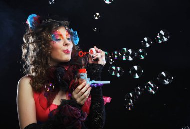 Yaratıcı makyajlı, sabun köpüğü üfleyen modaya uygun genç bir kadın. Bebek stili.