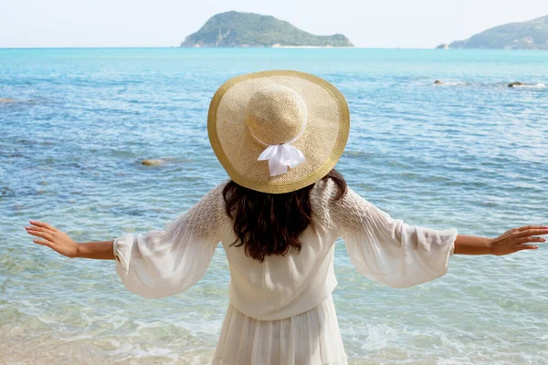 Junge Frau im Sommerkleid mit Strohhut mit Blick auf Himmel und Meer. — Stockfoto