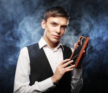 Profesyonel makyaj sanatçısı Studio, poz gölgeler paleti tutar. Duman arka planı. Genç Moda adam. yakın çekim