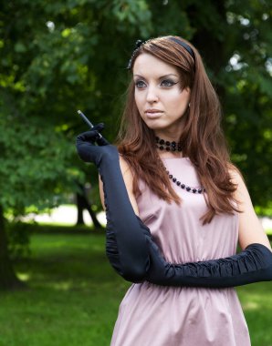 Güzel, zarif genç bayan parkta eğleniyor. Klasik stil.