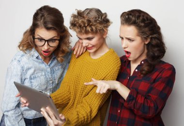 Üç hippi kız arkadaş dijital tablet kullanıyor.